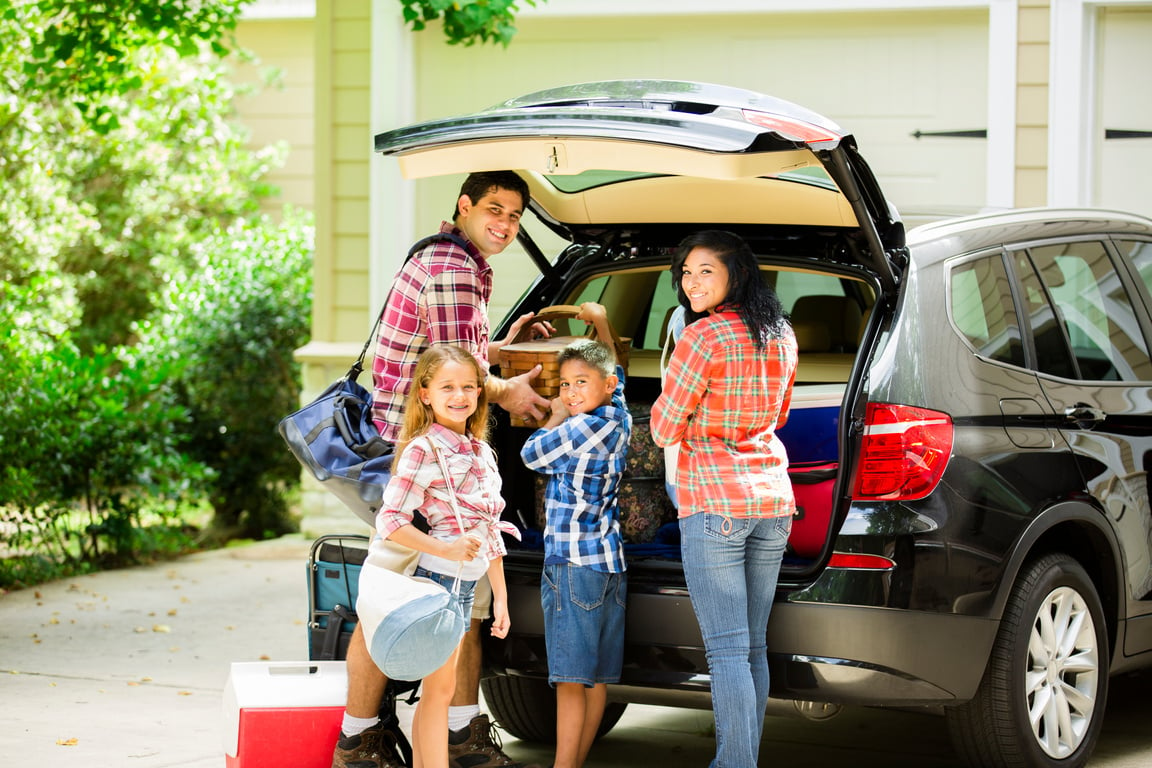 Family packing car to go on vacation. Parents, children.